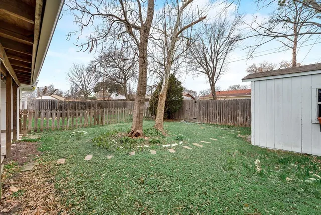 a view of a backyard with large trees and wooden fence
