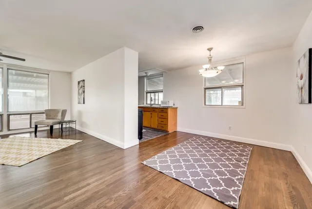 an empty room with kitchen view and wooden floor