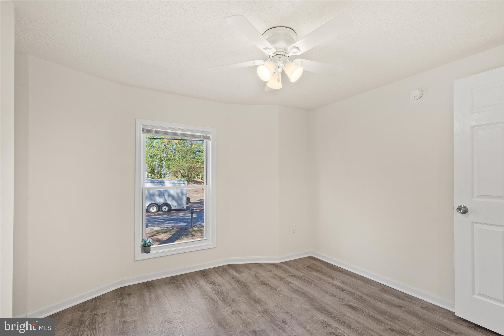 26465 Mason Webster Road Princess Anne, MD 21853 - Photo 26 of 56 an empty room with wooden floor chandelier fan and windows