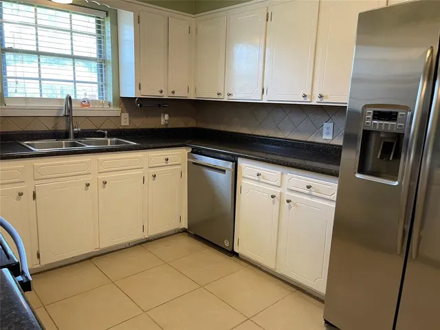 a kitchen with granite countertop white cabinets and stainless steel appliances
