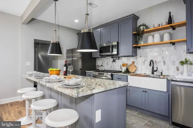 a kitchen with stainless steel appliances granite countertop a sink a stove a kitchen island and chairs with wooden floor