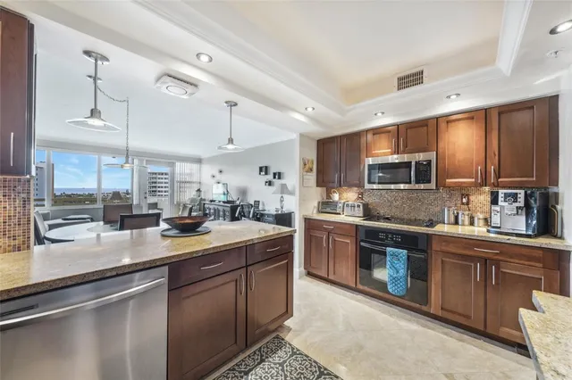 a kitchen with granite countertop a sink a counter top space stainless steel appliances and cabinets