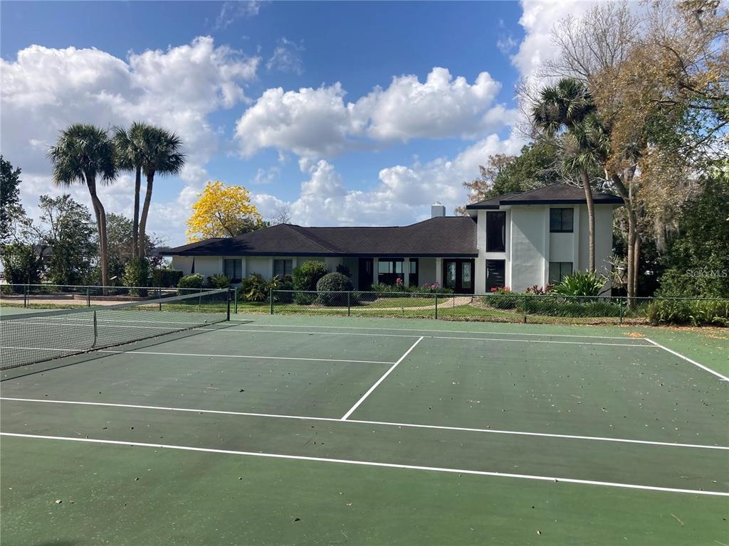 a view of a tennis ground with large trees