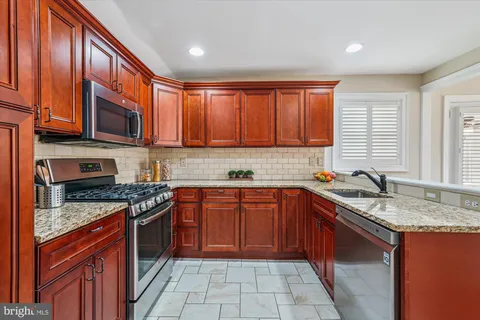 a kitchen with stainless steel appliances granite countertop wooden cabinets a sink and a stove