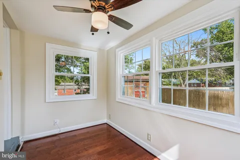 an empty room with wooden floor fan and windows