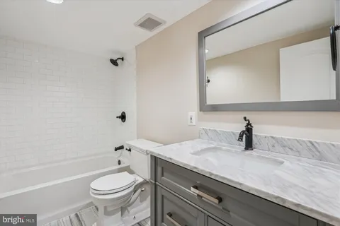 a bathroom with a granite countertop toilet a sink and a bathtub