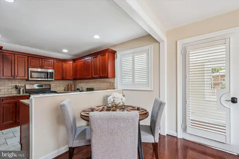 a kitchen with stainless steel appliances granite countertop a stove top oven a sink dishwasher a dining table and chairs with wooden floor