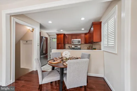 a open dining room with stainless steel appliances kitchen island granite countertop a dining table chairs and a refrigerator