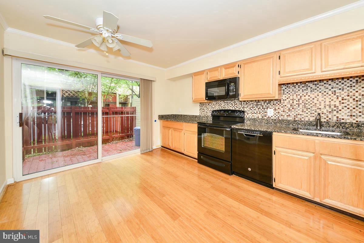 11187 Saffold Way Reston, VA 20190 - Photo 1 of 27 a kitchen with stainless steel appliances granite countertop a stove top oven a sink dishwasher a dining table and chairs with wooden floor