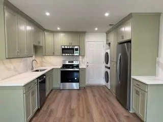a kitchen with stainless steel appliances kitchen island granite countertop a refrigerator a sink and wooden cabinets