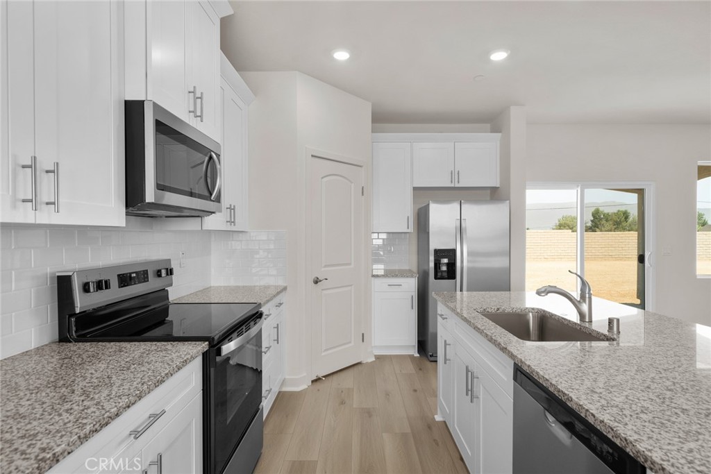 a kitchen with granite countertop kitchen island a sink appliances and cabinets