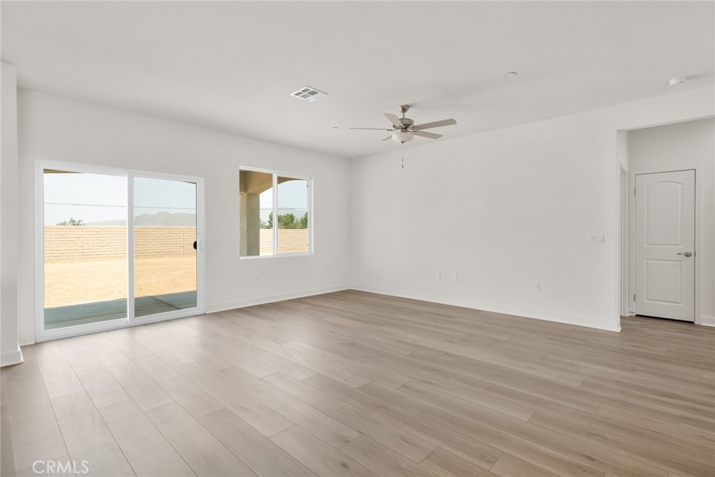 14574 Indigo Street Apple Valley, CA 92307 - Photo 3 of 6 an empty room with wooden floor chandelier fan and windows