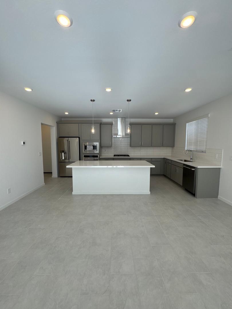 2442 West Maximo Way Phoenix, AZ 85085 - Photo 6 of 16 a large white kitchen with kitchen island a sink a stove and a refrigerator