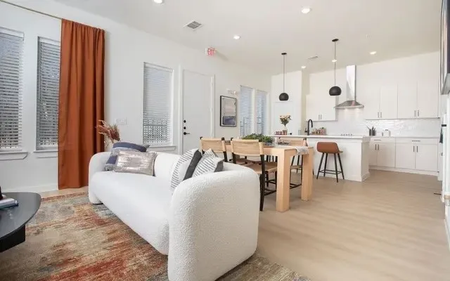 a living room with lots of white furniture and a large window