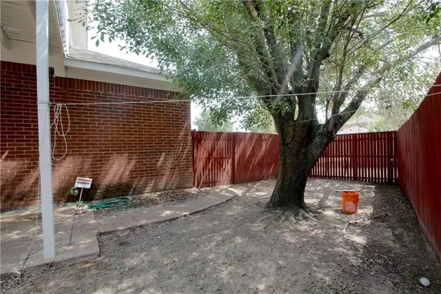 a backyard of a house with a tree and wooden fence