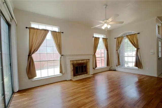 an empty room with wooden floor chandelier and fireplace