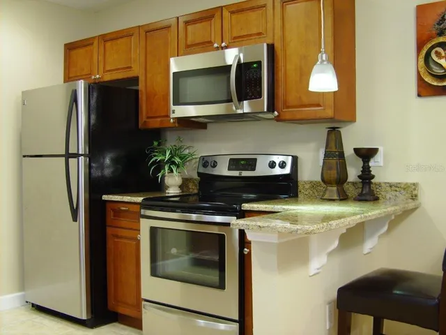 a kitchen with stainless steel appliances granite countertop a refrigerator microwave and stove top oven
