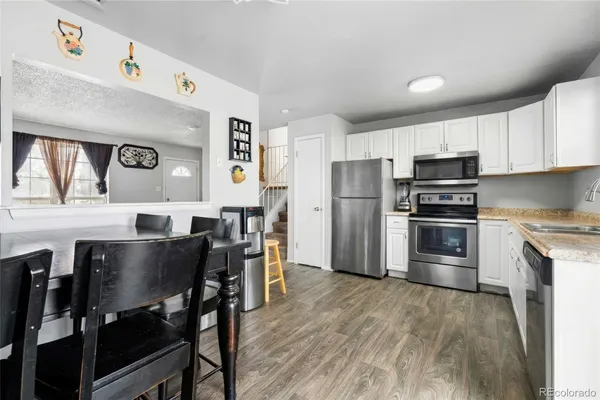 a kitchen with stainless steel appliances a table chairs microwave and refrigerator