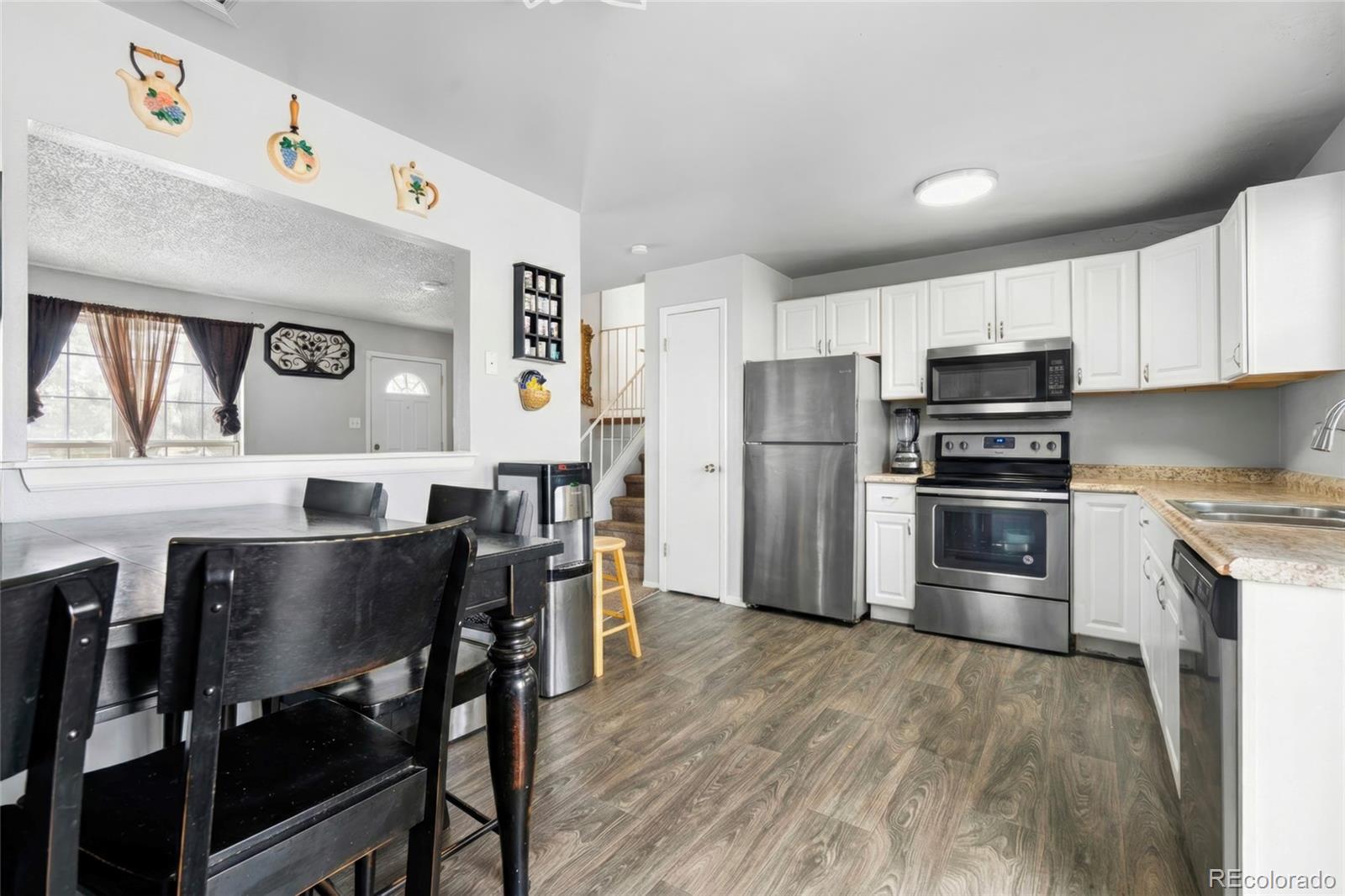 4609 Fontana Way Denver, CO 80239 - Photo 6 of 22 a kitchen with stainless steel appliances a table chairs microwave and refrigerator