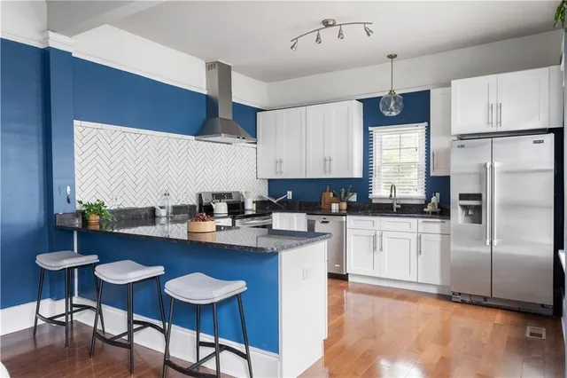 a kitchen with stainless steel appliances granite countertop a sink a stove a refrigerator cabinets and chairs