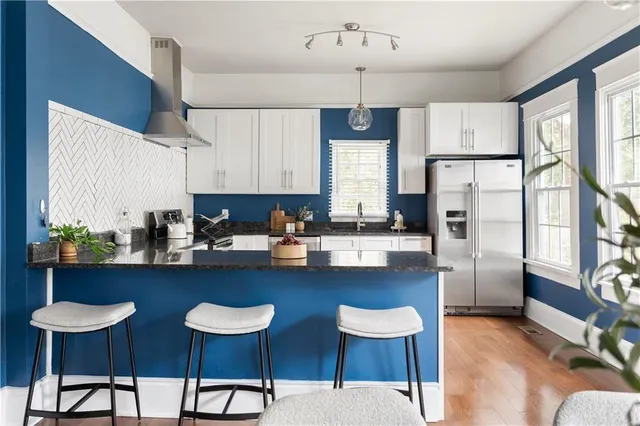 a kitchen with stainless steel appliances a dining table chairs refrigerator and sink