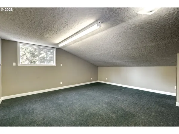 a view of an empty room with wooden floor and window