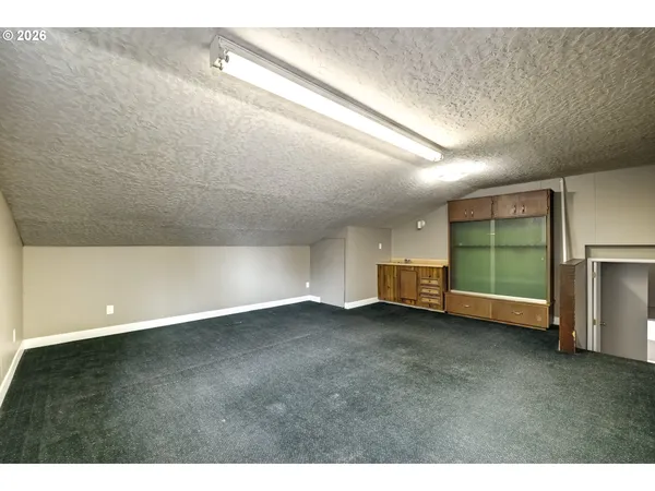 a view of an empty room with a window and kitchen view
