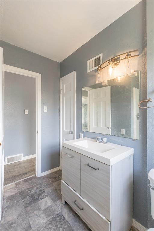 2841 Old Anson Road Abilene, TX 79603 - Photo 11 of 34 The bathroom features a vanity with a white countertop and an integrated sink, complemented by a mirror and overhead lighting