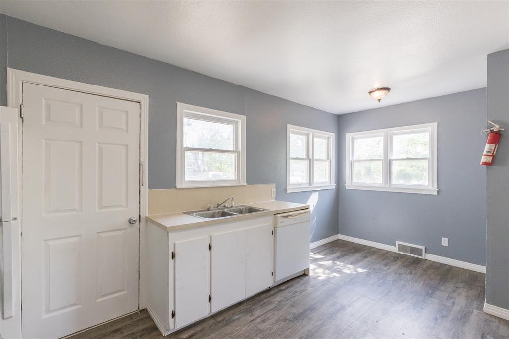 2841 Old Anson Road Abilene, TX 79603 - Photo 17 of 34 The property features a kitchen with light blue walls, white cabinetry, a double sink, and a dishwasher