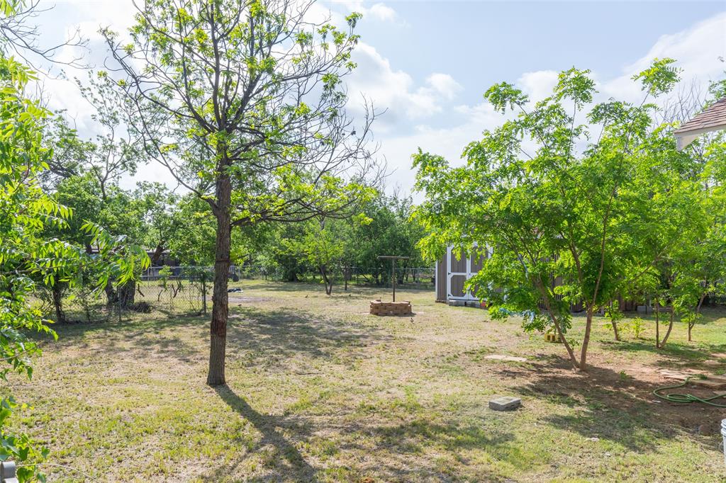 2841 Old Anson Road Abilene, TX 79603 - Photo 25 of 34 The property features a spacious yard with established trees, a storage shed, and a stone-built fire pit