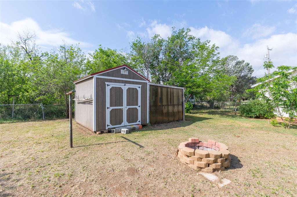 2841 Old Anson Road Abilene, TX 79603 - Photo 30 of 34 The property includes a spacious backyard with a lawn, a storage shed, and a stone fire pit