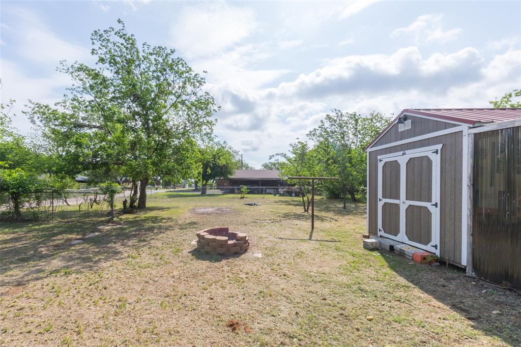 2841 Old Anson Road Abilene, TX 79603 - Photo 32 of 34 Expansive yard space featuring a storage shed with a red roof, a brick fire pit, and mature trees
