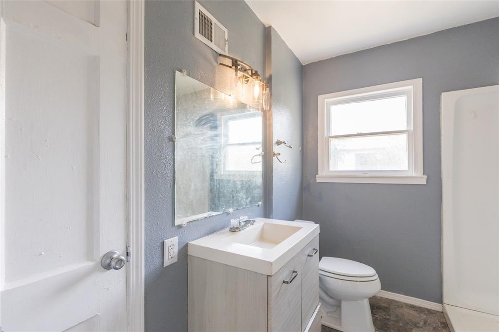 2841 Old Anson Road Abilene, TX 79603 - Photo 8 of 34 The bathroom features a vanity with a rectangular sink and cabinet storage, a toilet, and a window providing natural light