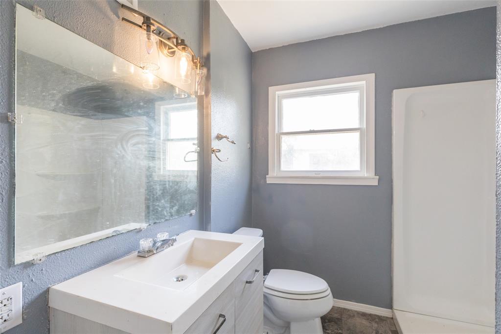 2841 Old Anson Road Abilene, TX 79603 - Photo 9 of 34 The bathroom features a vanity with an integrated sink, a wall-mounted mirror, and a light fixture with exposed bulbs