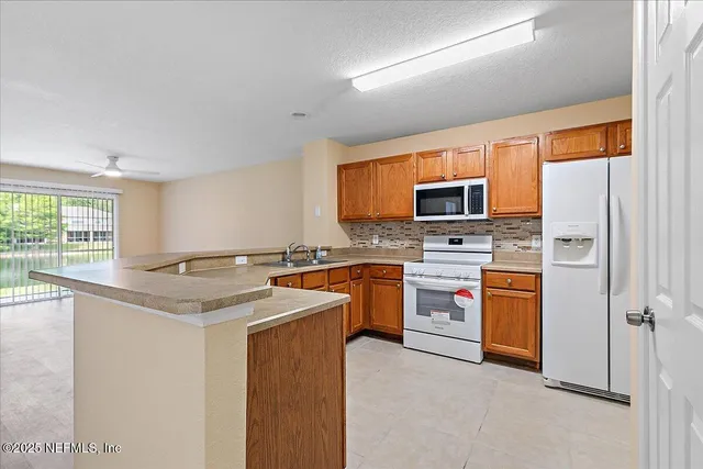 a kitchen with stainless steel appliances granite countertop a stove top oven a sink dishwasher a refrigerator and a dining table with wooden floor