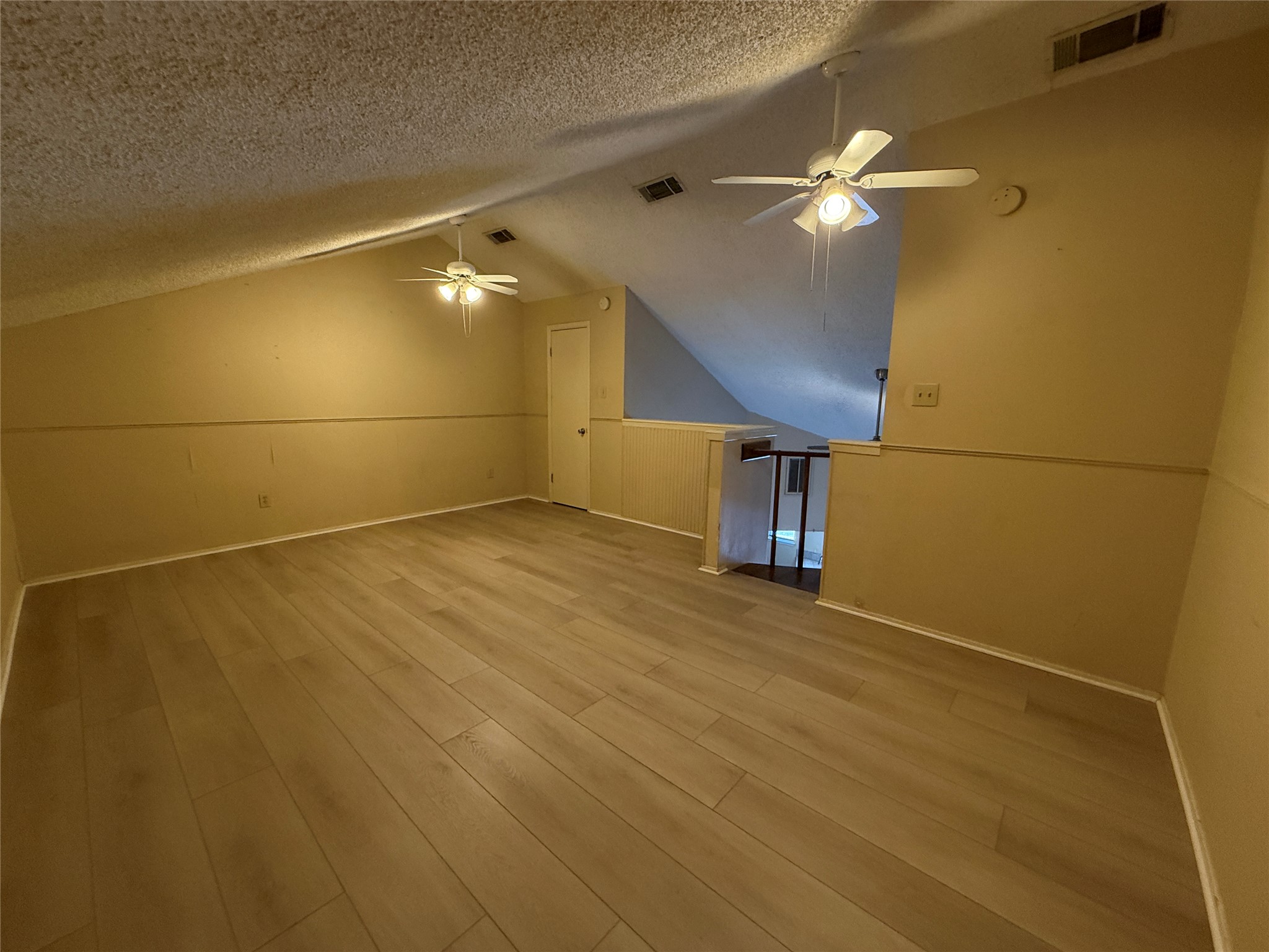 2500 Burleson Road, Unit 221 Austin, TX 78741 - Photo 4 of 18 Bonus room featuring ceiling fan, light wood-style floors, and a textured ceiling