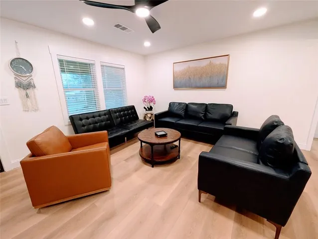 a living room with furniture and a black ceiling fan