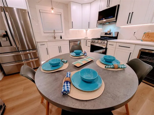 a kitchen with stainless steel appliances granite countertop a stove a table and chairs
