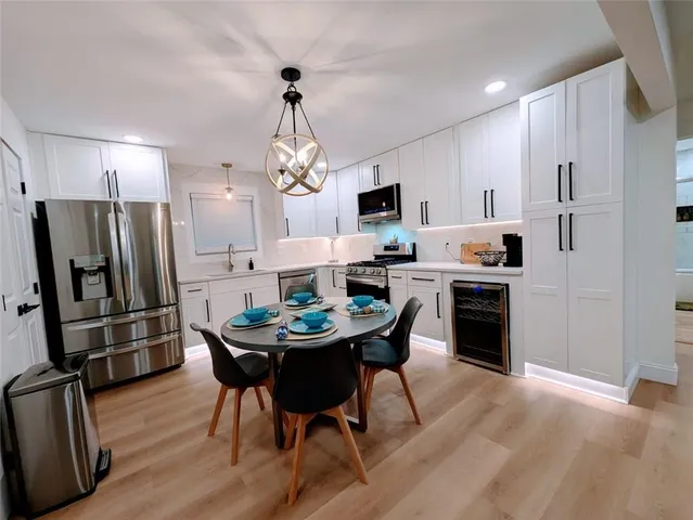 a kitchen with stainless steel appliances a dining table chairs refrigerator and microwave