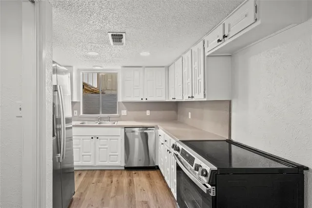a view of a kitchen cabinets a refrigerator and wooden floor