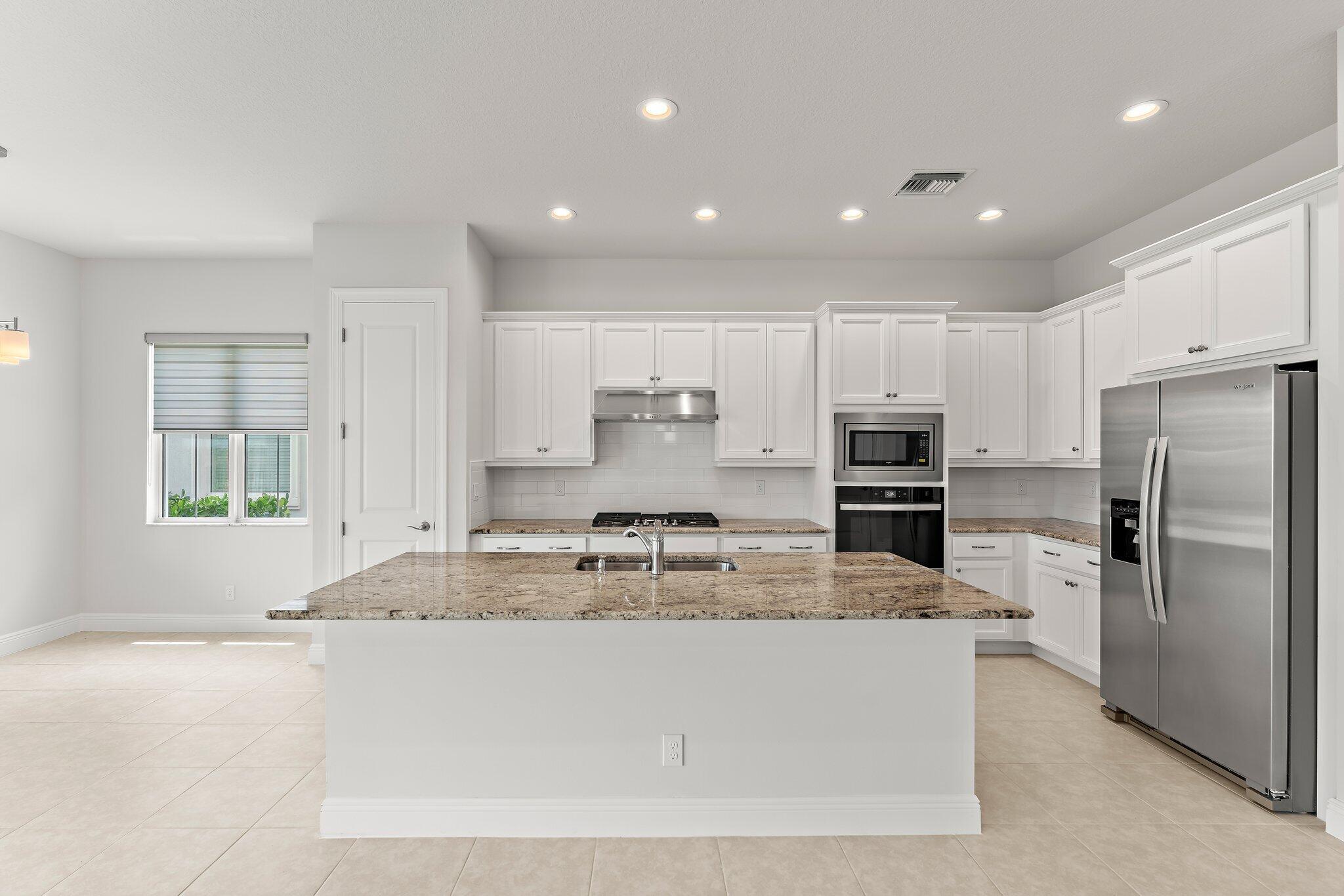 12622 Nautilus Circle Palm Beach Gardens, FL 33412 - Photo 12 of 66 a large kitchen with kitchen island a large counter top stainless steel appliances and cabinets