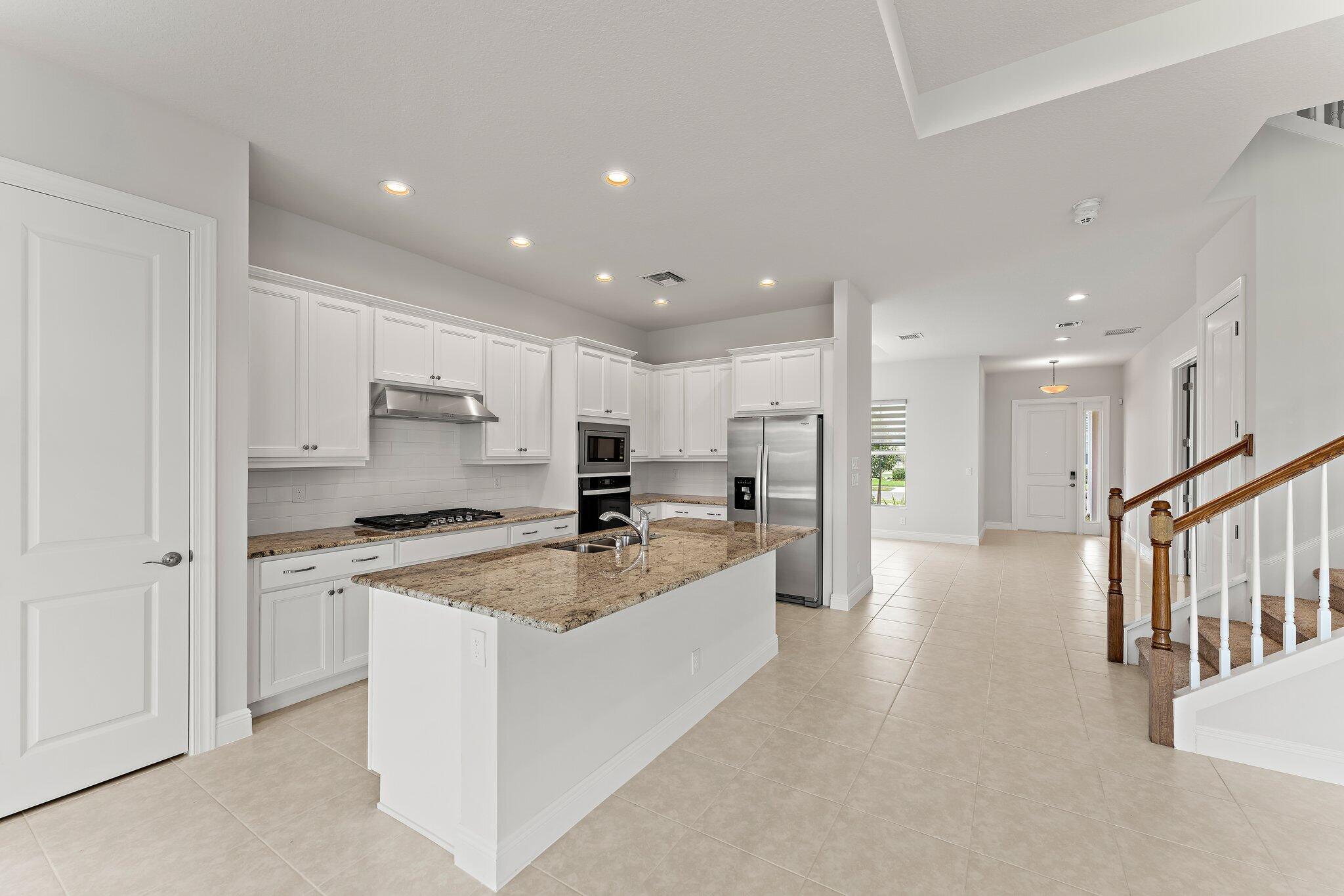 12622 Nautilus Circle Palm Beach Gardens, FL 33412 - Photo 13 of 66 a view of a kitchen with kitchen island a stove a sink a refrigerator and white cabinets