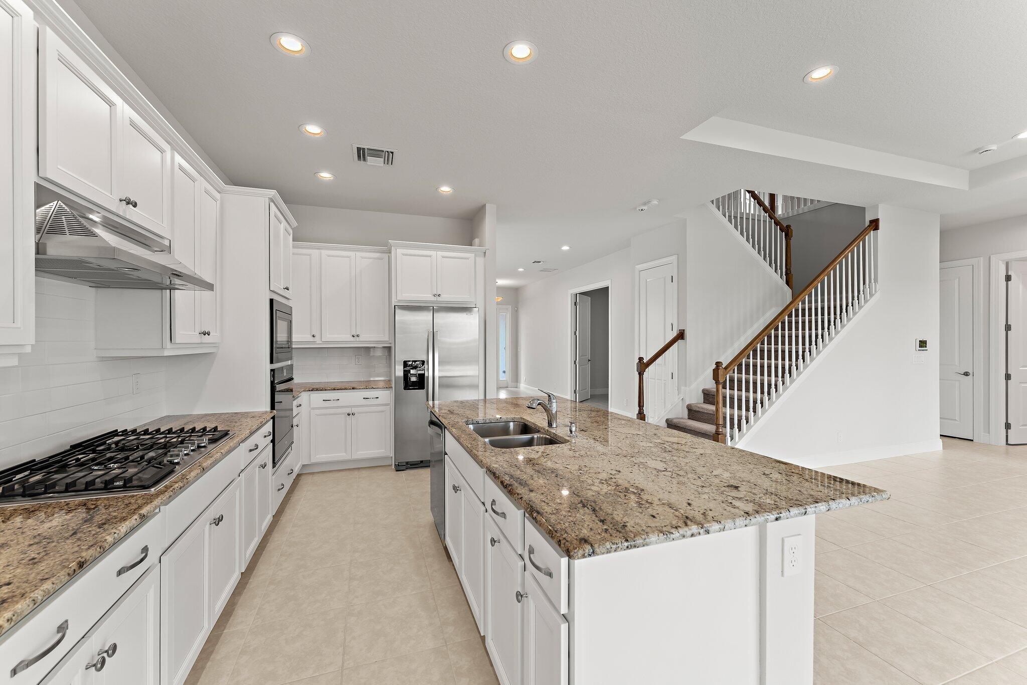 12622 Nautilus Circle Palm Beach Gardens, FL 33412 - Photo 14 of 66 a kitchen with a stove a sink a refrigerator and white cabinets with wooden floor