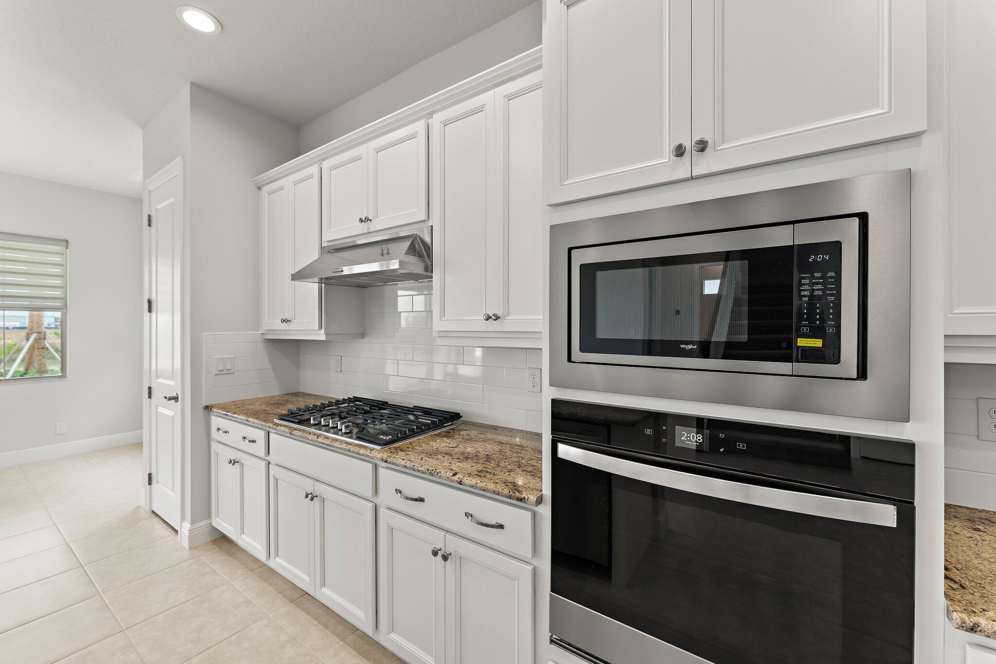 12622 Nautilus Circle Palm Beach Gardens, FL 33412 - Photo 15 of 66 a kitchen with white cabinets and appliances