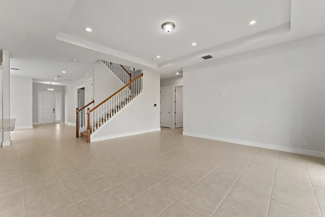 a view of an empty room and kitchen with granite countertop a large window
