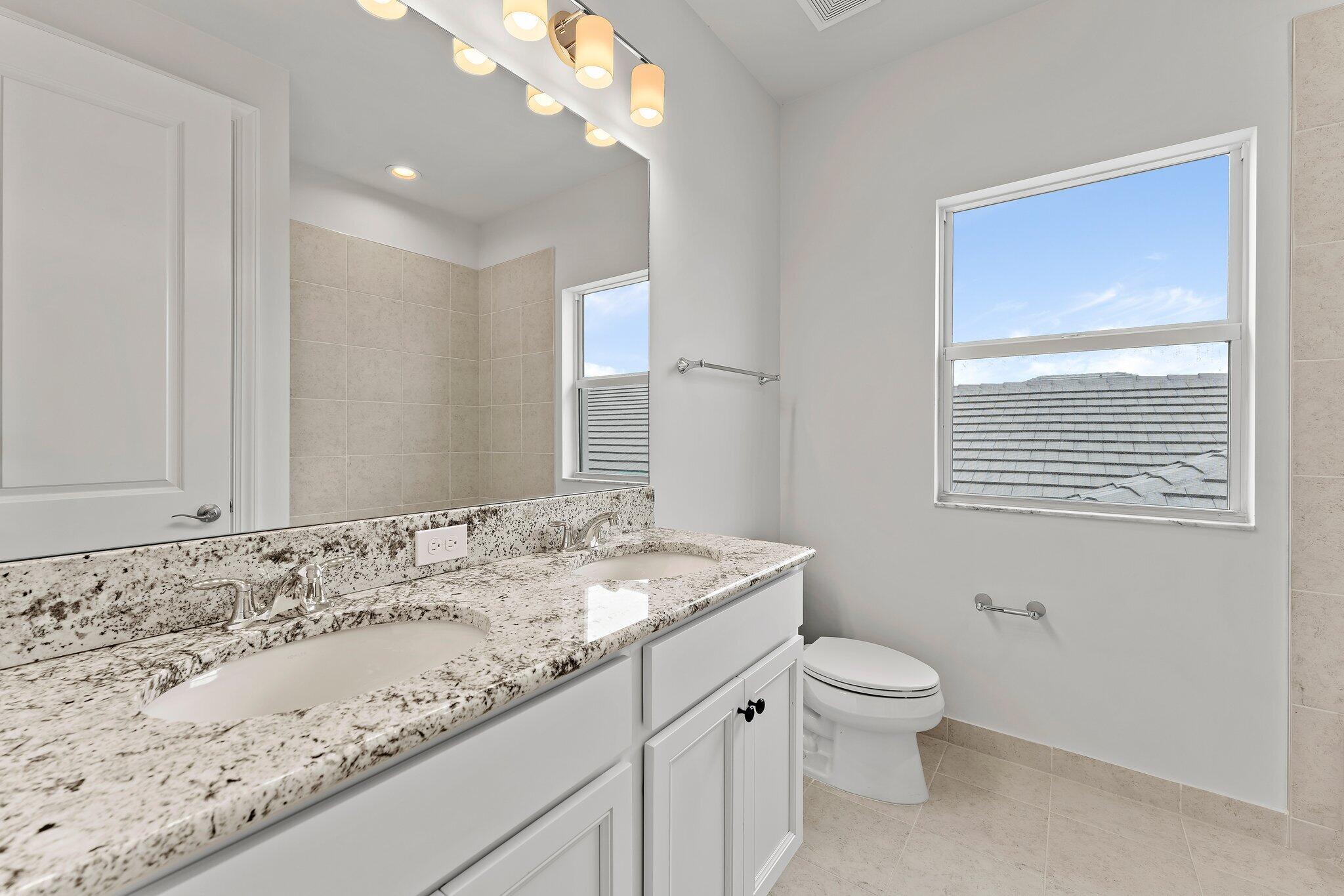 12622 Nautilus Circle Palm Beach Gardens, FL 33412 - Photo 38 of 66 a bathroom with a granite countertop sink a toilet and mirror
