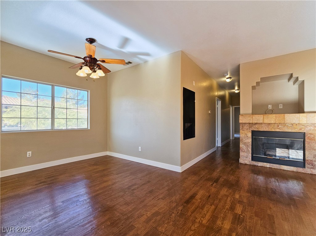 1851 Hillpointe Road, Unit 2124 Henderson, NV 89074 - Photo 12 of 24 Unfurnished living room featuring a tile fireplace, dark wood-style flooring, baseboards, and ceiling fan