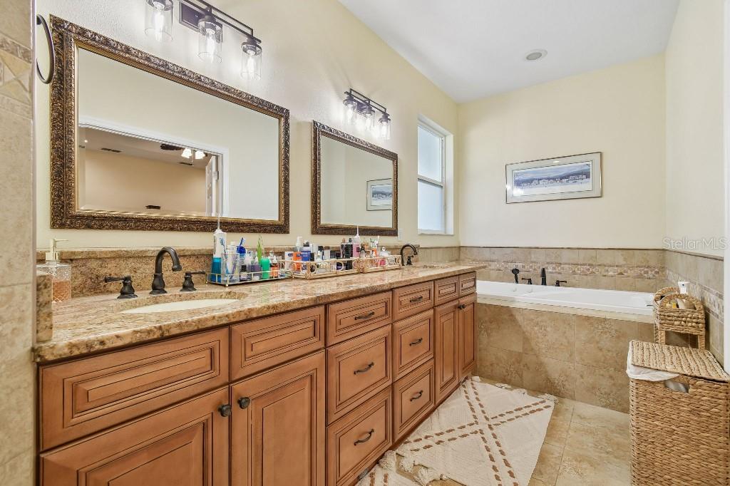 3302 Jap Tucker Road Plant City, FL 33566 - Photo 27 of 44 a bathroom with a granite countertop double vanity sink a mirror and bathtub