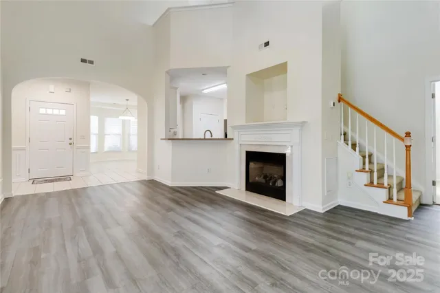 a view of an empty room with wooden floor and a fireplace