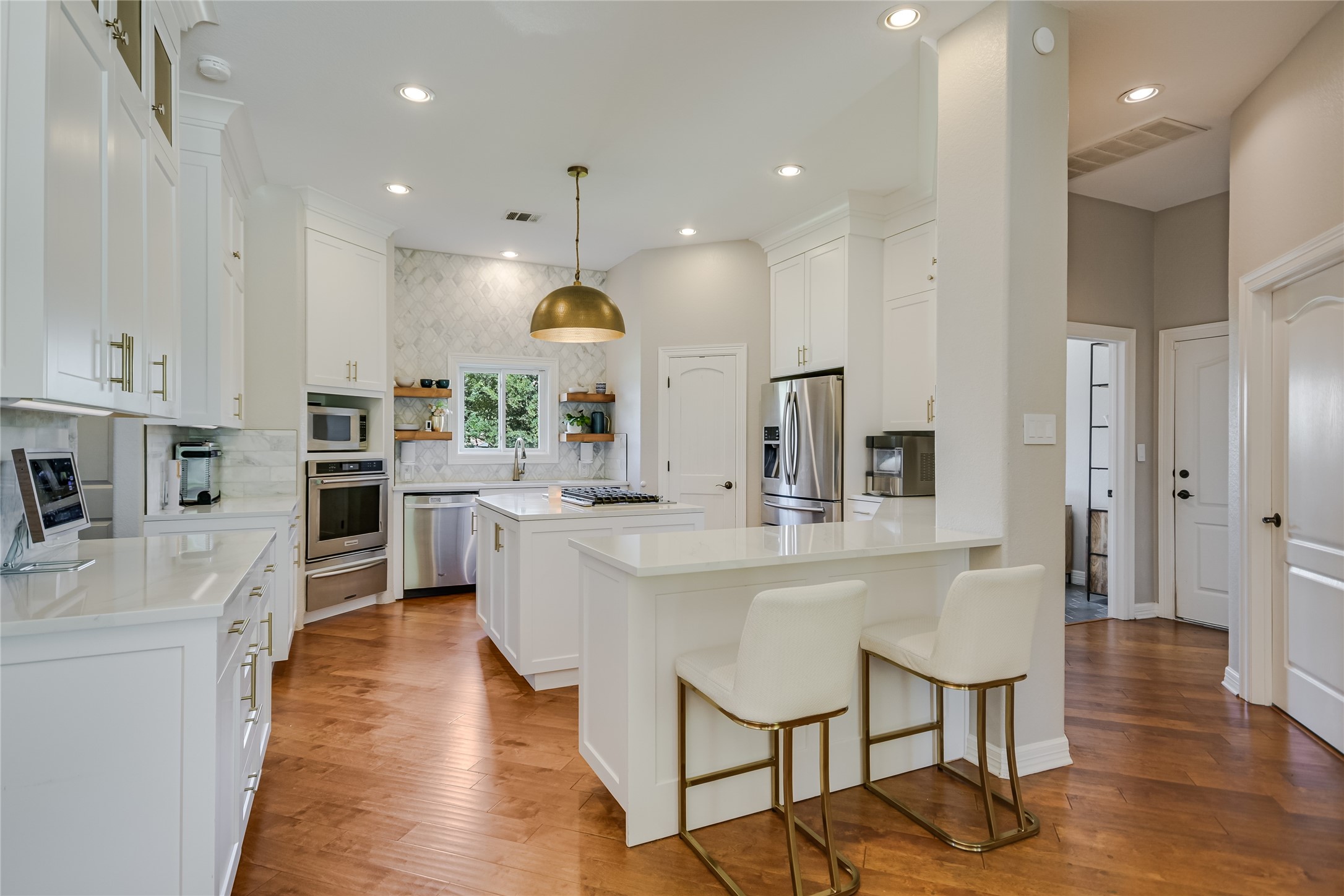 100 Dovetail Lane Georgetown, TX 78628 - Photo 5 of 34 Highly functional and entertaining gourmet kitchen features quartz counters, stainless appliances, white cabinetry, center island gas cooktop, and floating shelves.